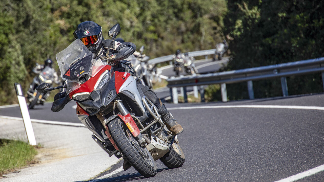 Motorradgruppe in einer Kurve, vorn eine rote Reiseenduro Motorradgruppe in einer Kurve, vorn eine rote Reiseenduro